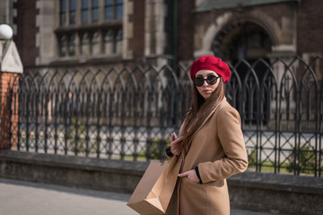 Young beautiful woman with long brown hair in sunglasses on a walk on a cloudy day. Fashionable sexy girl. Street fashion look. Cute student. Shopping.