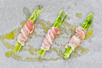 Mini asparagus in bacon on a baking sheet. White background, top view.