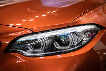 Headlight of orange modern car with LED light