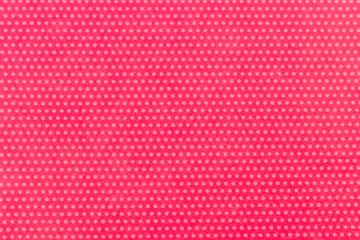 Textile background, fuchsia with a print in white polka dots. View from above.