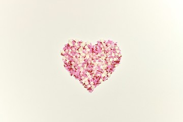 Pink heart from figured sugar topping on a light surface. View from above.