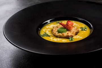 Homemade pumpkin cream soup on dark plate