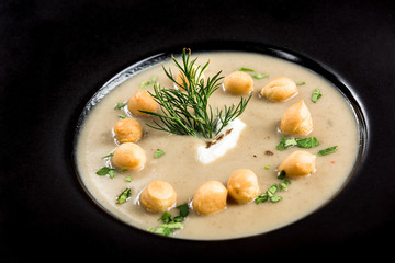 Homemade mushroom cream soup served on dark plate