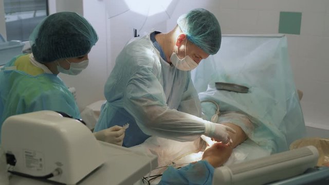 Surgeon treats wounds and bandages patient leg after sclerotherapy operation