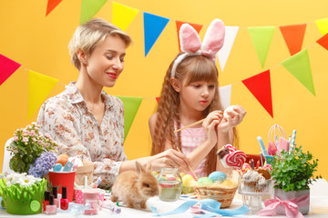 happy family mother and child girl paints eggs for Easter at home. Family celebration and home decoration for spring holiday.