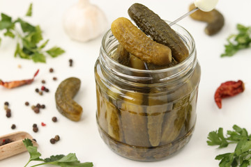Pickled gherkins in a glass jar on a white background, top view