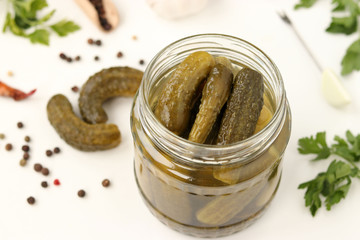 Pickled gherkins in a glass jar on a white background, top view