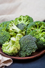 Fresh green organic broccoli in brown plate and linen napkin.