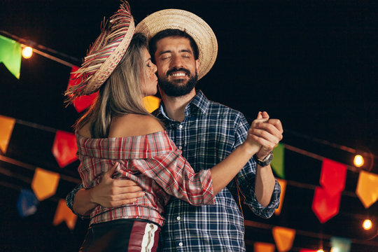 Brazilian couple wearing traditional clothes for Festa Junina - June festival - dancing under the night sky