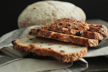 Sliced  raisin  bread on black background. Crumbs and fresh Bread slices close up. Bakery, food concept. Top view .Fresh large homemade bread 