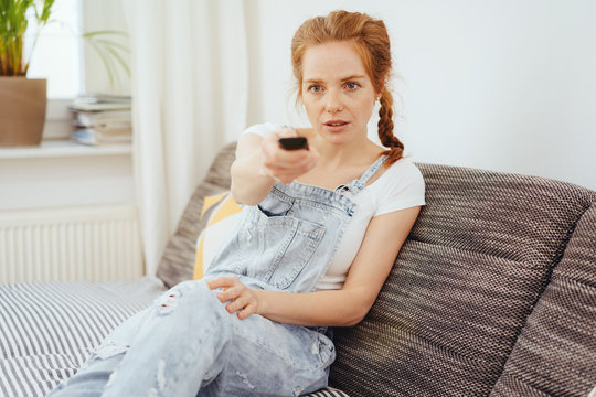 Young redhead woman watching television