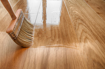 a large wooden brush covers the parquet with lacquer - obrazy, fototapety, plakaty
