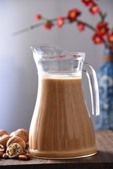 glass of tea and jug of milk on wooden table