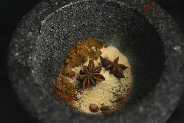 A mixture of spices in a stone pestle and mortar ready to be ground