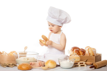 Little cook with a bagel in her hands, chef suit. Cooking child lifestyle concept. Toddler playing