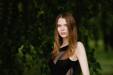 portrait of a beautiful girl with freckles on the background of foliage