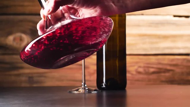 Wein. Rotwein, der in Weinglas &uuml;ber dunklem Hintergrund gie&szlig;t.