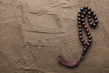 Prayer beads on brown background, space for text