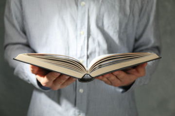 Man hold book in hands against grey background