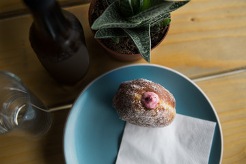 A fresh fruit doughnut served on a plate with a drink at a cafe on a wooden table