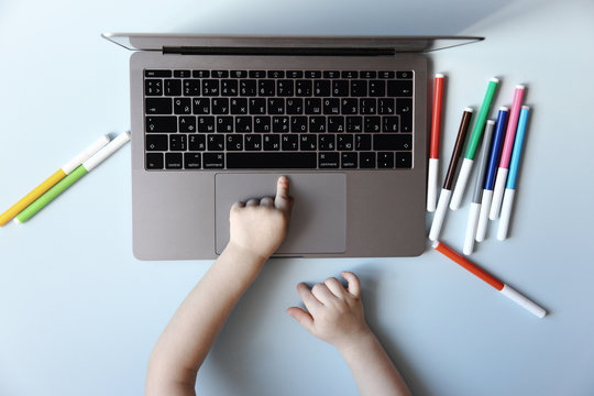 Kid Hands Typing On Laptop Keyboard On Blue Background, Top View