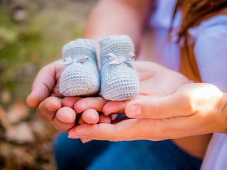 Newborn shoes on father and mother hands. Maternity