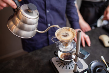 A barista brewing a pour over coffee in a coffee shop