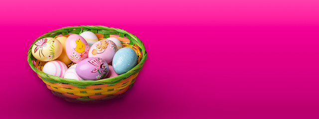 Fototapeta na wymiar Wicker basket with Easter eggs hand painted on color tabletop background