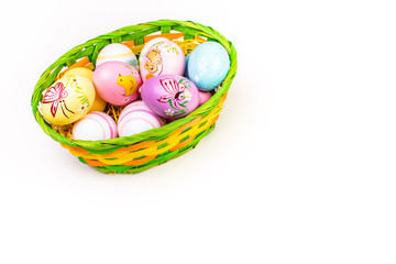Wicker basket with Easter eggs hand painted on white tabletop background
