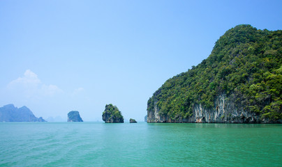 Beautiful view of the islands and ocean. Green sheer cliffs cover tropic plants. Archipelago in Andaman Sea, Thailand.