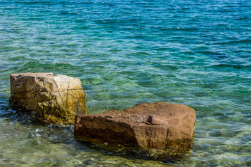 tropic sea rocky waterfront calming idyllic scenic landscape nature view with stones and vivid blue water, summer warm weather time, copy space
