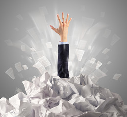 Hand coming out from a huge paper pile
