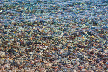 transparent water and unfocused colorful stone bottom abstract unfocused fuzzy natural scenic background, summer concept photography