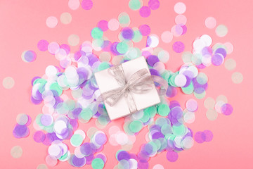 Gift box on pink background with confetti.