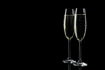 Glasses of champagne on black background, space for text