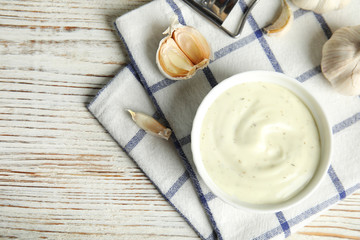 Flat lay composition with garlic sauce on wooden background. Space for text