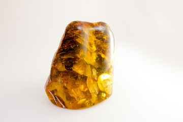Multi-colored amber stone with yellow and red parts with the tree bark on the inside. Amber for jewelry. Precious stones.