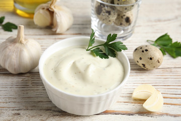 Composition with bowl of garlic sauce on wooden table