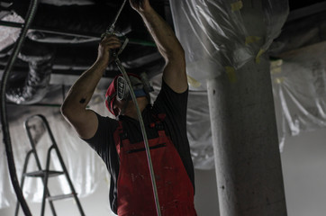 The man in the protective form paints the ceiling from the spray gun