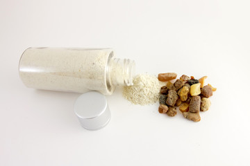 Amber powder in a clear bottle. Used for processing amber stones. Comosite with amber powder and large amber stones on bulom background