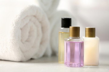 Mini bottles with cosmetic products and towels on table. Hotel amenities