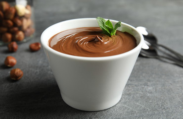 Ceramic bowl with sweet chocolate cream and mint on table