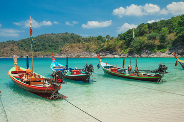 Beautiful exotic boats in lagoon. Seascape with transparent azure water and coast with tropical forest. Thailand. Andaman Sea. 