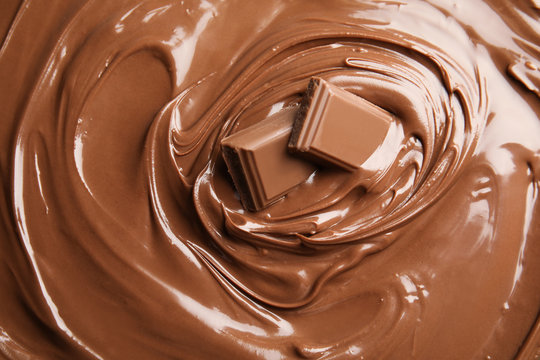 Sweet tasty chocolate cream with pieces as background, closeup