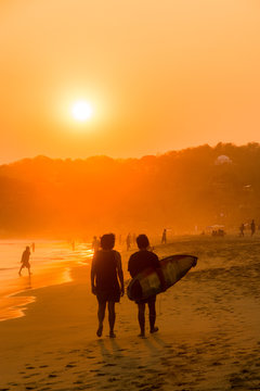 Surfeur marchant sur la plage. Couch&eacute; de soleil plage de Zipolite, Oaxaca, Mexique.