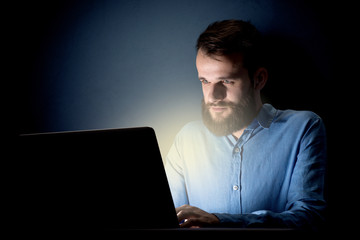 Young handsome businessman working late at night in the office with a dark background