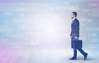 Handsome businessman walking in suit with briefcase on his hand and online communication concept around
