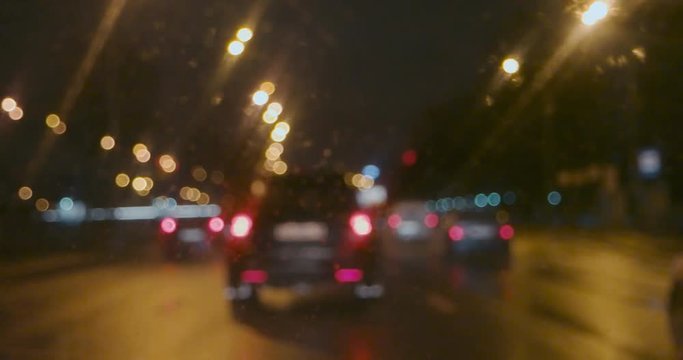Slow moving cars with rear light on in the rain look through wet window