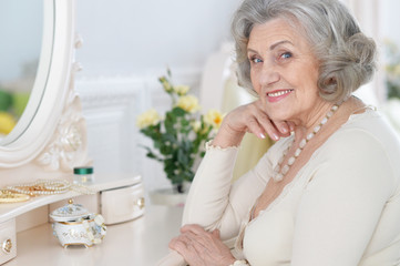 Fototapeta na wymiar Close up portrait of happy senior woman sitting near dressing table