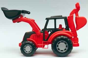 Toy red tractor on a light background. Close-up, children's pear industrial car, Plastic wheel loader.